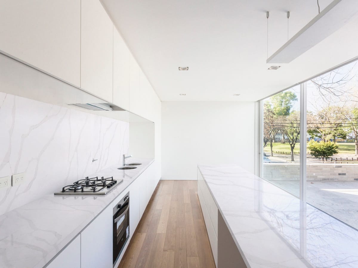 Cocina con salpicadero e isla de Purastone Calacatta Gold