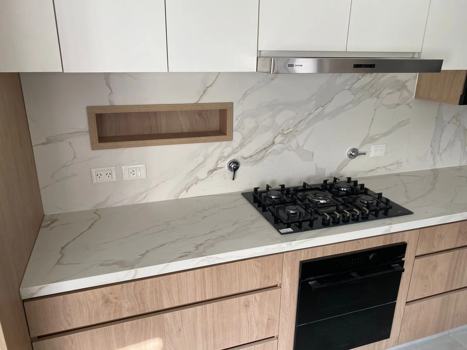 Cocina con mesada y frente de piedra blanca veteada y un nicho de madera